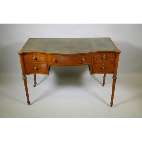 1009 - A Victorian satinwood serpentine front five drawer kneehole dressing table, with inset leather top, ... 