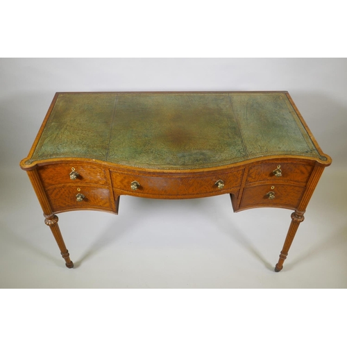 1009 - A Victorian satinwood serpentine front five drawer kneehole dressing table, with inset leather top, ... 