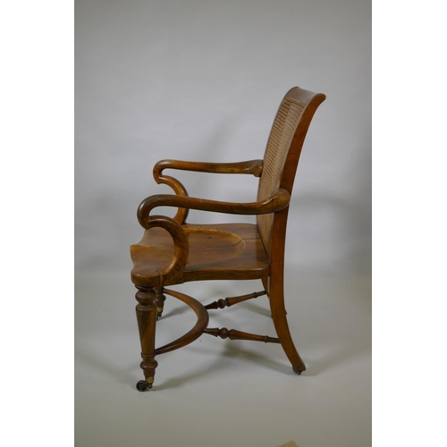 1016 - An early C19th Irish walnut elbow chair with bergere caned back, shepherd's crook arms and saddle se... 