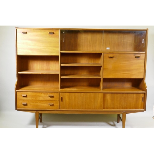 1030 - A mid century teak side cabinet with sliding glass doors and open shelves over two drawers and cupbo... 