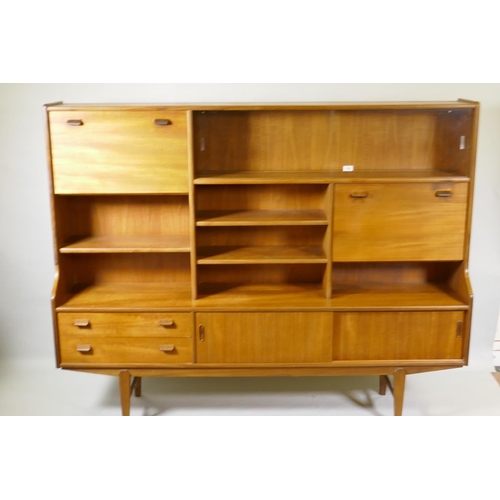 1030 - A mid century teak side cabinet with sliding glass doors and open shelves over two drawers and cupbo... 