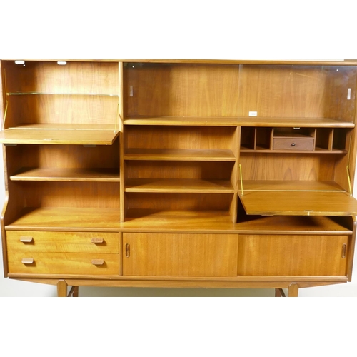 1030 - A mid century teak side cabinet with sliding glass doors and open shelves over two drawers and cupbo... 