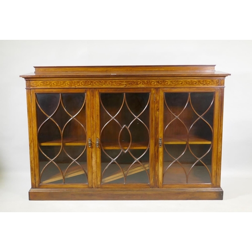 1064 - A Victorian mahogany bookcase, with inlaid frieze over three glazed doors, with five barred decorati... 