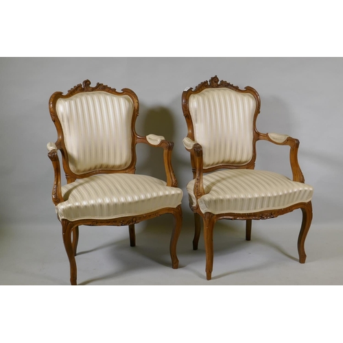 1073 - A pair of C19th French carved beechwood open armchairs with shaped backs, raised on cabriole support... 