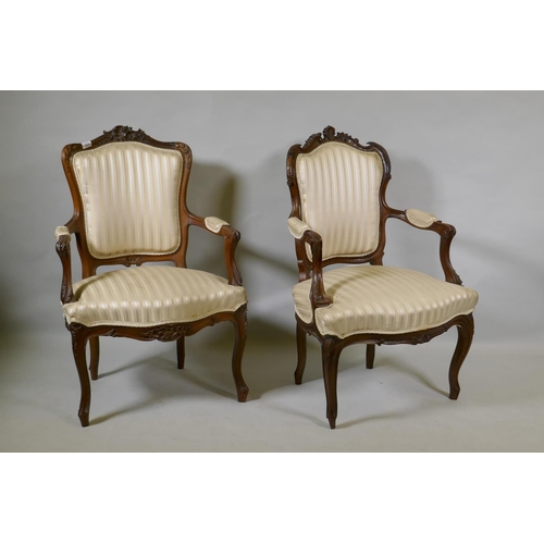 1074 - Two C19th French carved beechwood open armchairs, with shaped backs, raised on cabriole supports