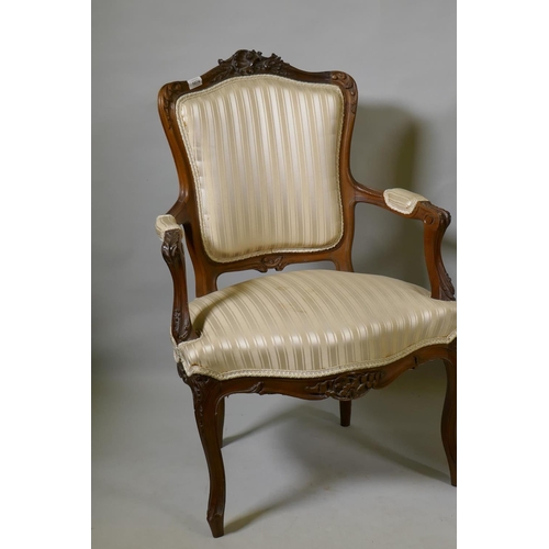 1074 - Two C19th French carved beechwood open armchairs, with shaped backs, raised on cabriole supports