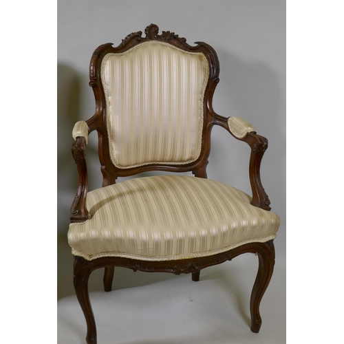 1074 - Two C19th French carved beechwood open armchairs, with shaped backs, raised on cabriole supports