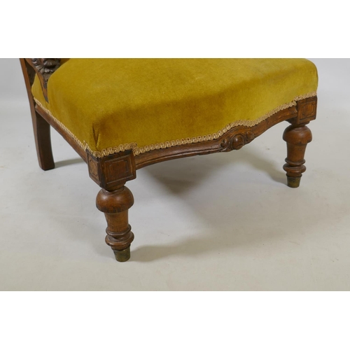 1076 - A C19th oak nursing chair with carved lion mask decoration, raised on turned supports