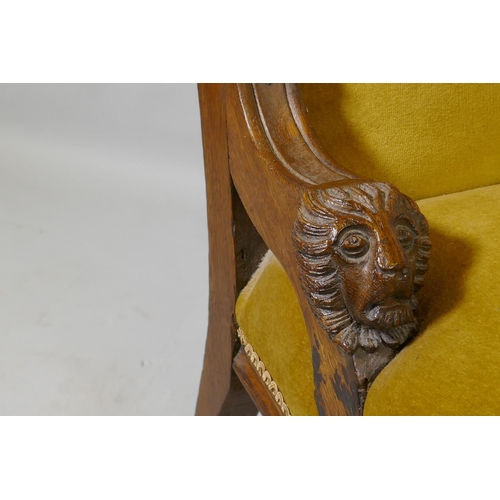 1076 - A C19th oak nursing chair with carved lion mask decoration, raised on turned supports