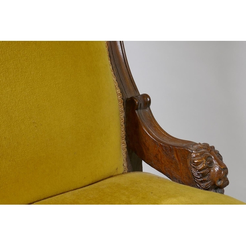 1076 - A C19th oak nursing chair with carved lion mask decoration, raised on turned supports