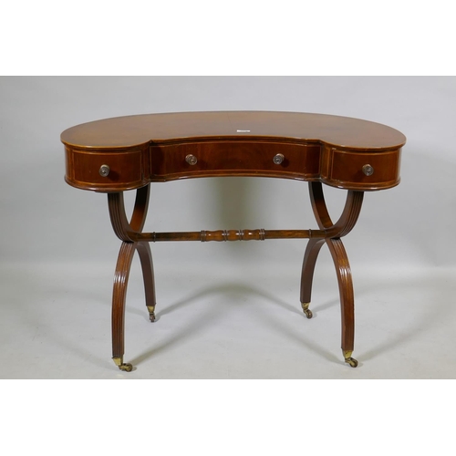 1079 - A Victorian inlaid mahogany kidney shaped desk/dressing table, raised on reeded cross frame end supp... 