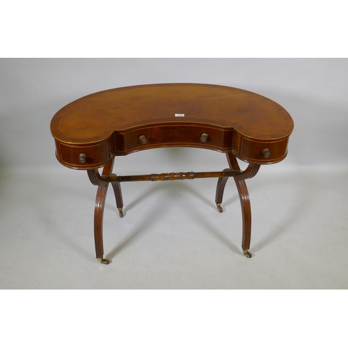 1079 - A Victorian inlaid mahogany kidney shaped desk/dressing table, raised on reeded cross frame end supp... 