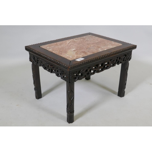 1080 - A Chinese carved and pierced hardwood table with an inset rouge marble top and bamboo shoot decorati... 