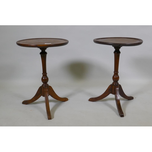 1082 - A pair of solid yew wood wine tables with dished tops, raised on turned columns with splay supports,... 