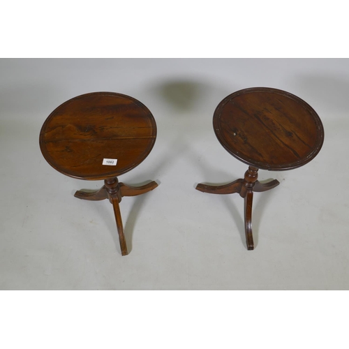 1082 - A pair of solid yew wood wine tables with dished tops, raised on turned columns with splay supports,... 