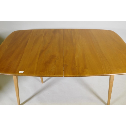 1090 - An Ercol Grand Windsor blond elm and beech extending dining table Model 444, and six matching Ercol ... 