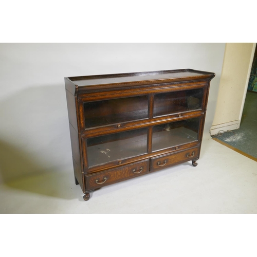 1111 - A Globe Wernicke style oak bookcase, two sections on a base of two drawers, raised on cabriole suppo... 