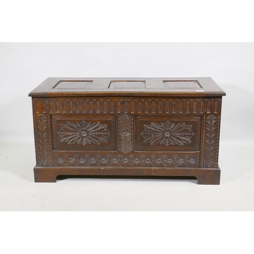 1144 - An oak coffer, the top with three fielded panels, the front with  carved frieze and double pane... 