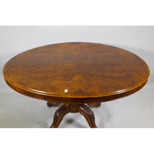 1169 - A Victorian figured walnut tilt top breakfast table, the oval top raised on a carved and turned colu... 