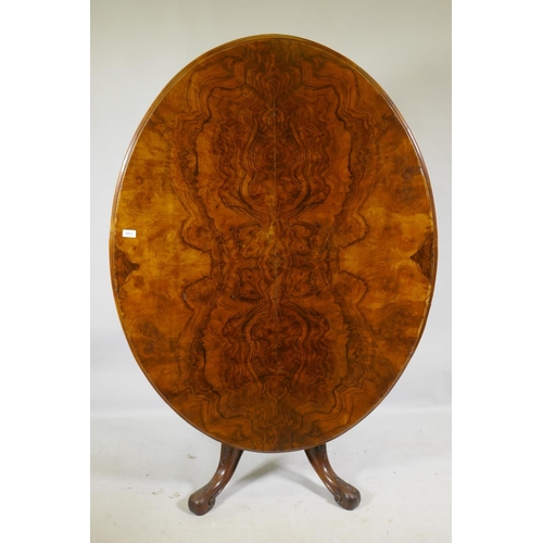 1169 - A Victorian figured walnut tilt top breakfast table, the oval top raised on a carved and turned colu... 