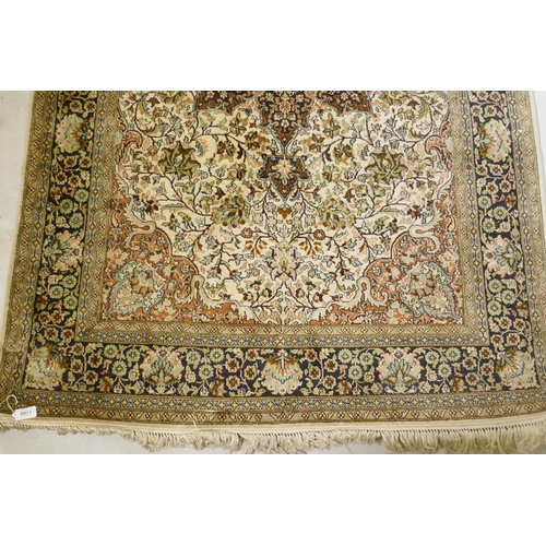 1180 - An Oriental silk carpet with floral designs and central medallion on a cream and faded terracotta fi... 