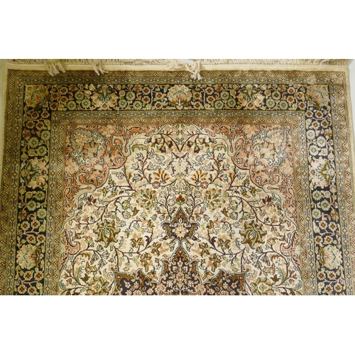 1180 - An Oriental silk carpet with floral designs and central medallion on a cream and faded terracotta fi... 