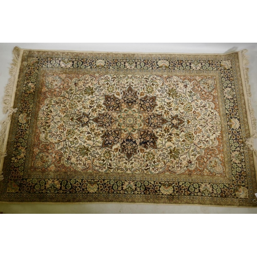 1180 - An Oriental silk carpet with floral designs and central medallion on a cream and faded terracotta fi... 