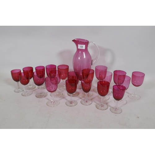 129 - A quantity of matched cranberry coloured drinking glasses and a carafe, 27cm high