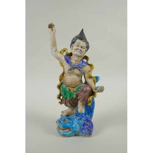 133 - A Chinese Sancai glazed porcelain Lohan standing on a carp, 27cm high