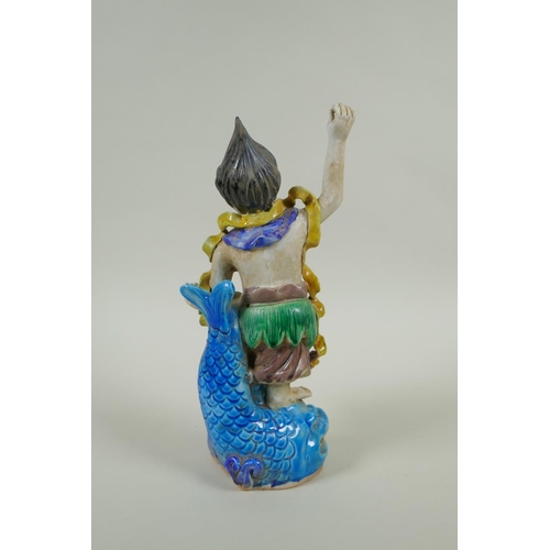 133 - A Chinese Sancai glazed porcelain Lohan standing on a carp, 27cm high