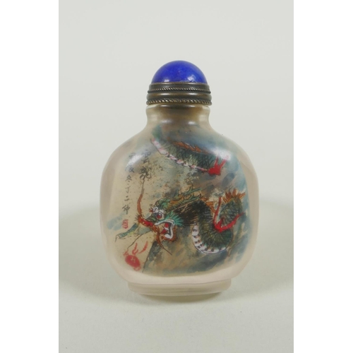 135 - A Chinese reverse decorated glass snuff bottle on a ring, decorated with a green dragon and a red le... 