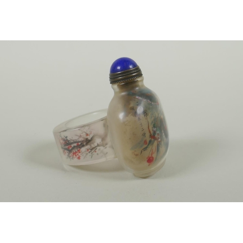 135 - A Chinese reverse decorated glass snuff bottle on a ring, decorated with a green dragon and a red le... 