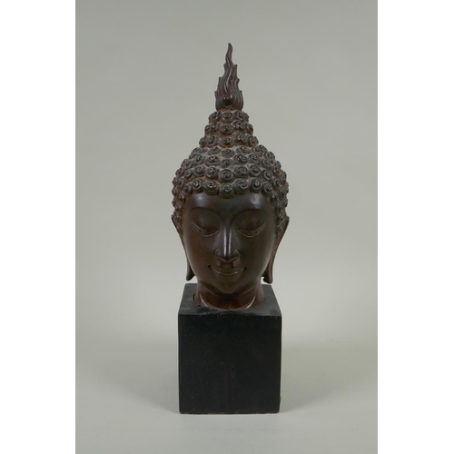 136 - A Thai bronzed metal head bust of Buddha, on a display stand, 35cm high