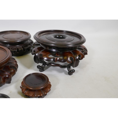 179 - Nine Chinese hardwood vase stands with carved lotus decoration, and a carved jar cover