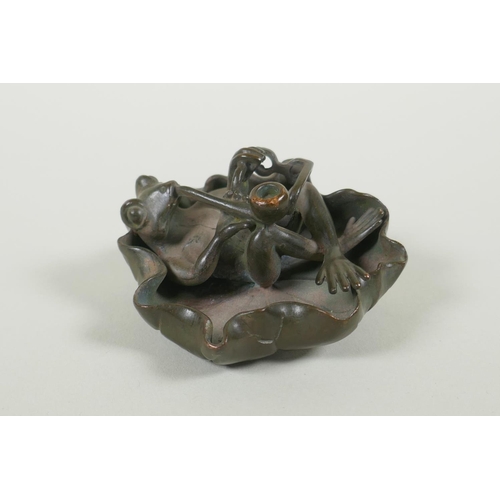 191 - A bronze figure of a smoking frog reclining on a lily pad, 8cm diameter