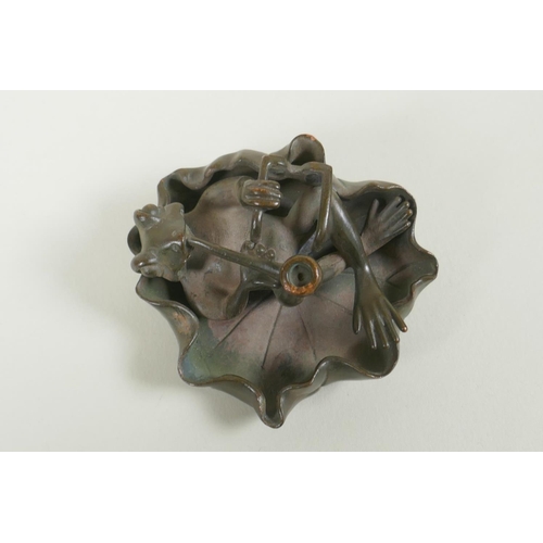 191 - A bronze figure of a smoking frog reclining on a lily pad, 8cm diameter