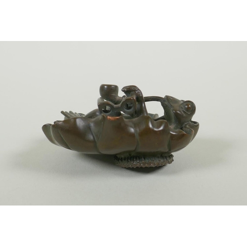 191 - A bronze figure of a smoking frog reclining on a lily pad, 8cm diameter