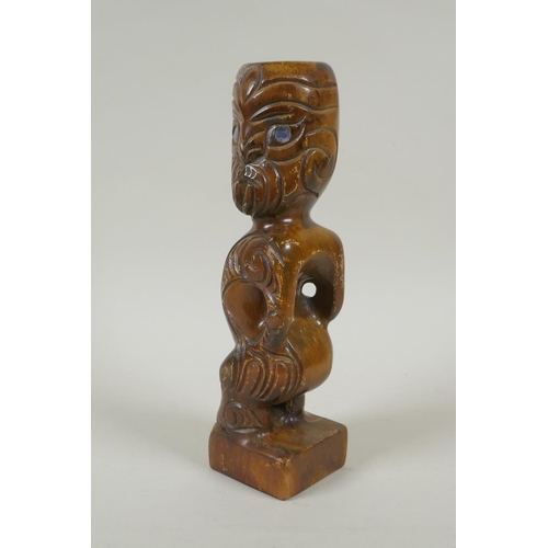 222 - A Maori carved wood Tiki figure with abalone eyes, 28cm high