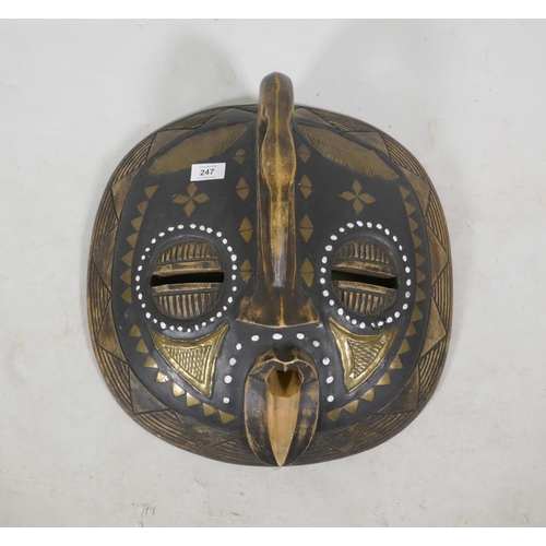 247 - An African tribal mask, inlaid with brass and shells, 43cm diameter