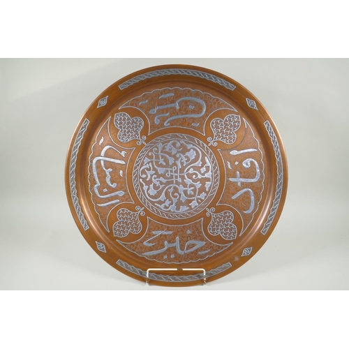 43 - An Islamic silver overlaid copper tray with caligraphic script decoration, 55cm diameter