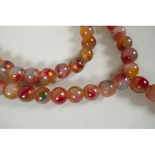 614 - A string of multicolour hardstone/jade mala beads with the remnants of gilt lustre, 122cm long