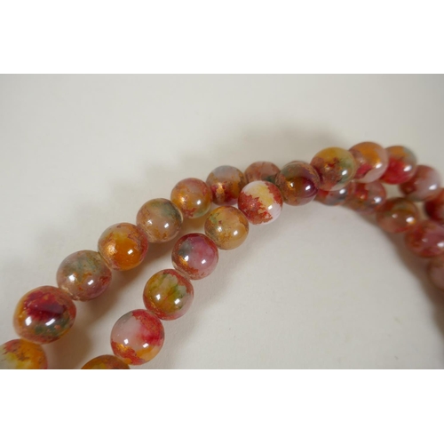 614 - A string of multicolour hardstone/jade mala beads with the remnants of gilt lustre, 122cm long