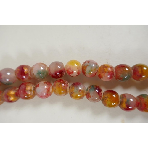 614 - A string of multicolour hardstone/jade mala beads with the remnants of gilt lustre, 122cm long