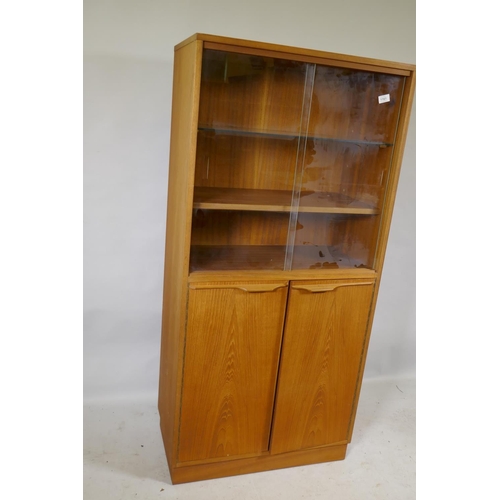 1223 - A mid century teak cabinet, with sliding glass doors over two cupboards, 69 x 36 x 144cm