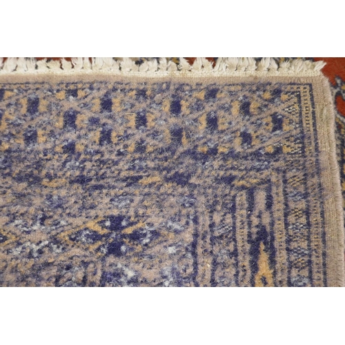 1180 - A Persian wool rug with a triple diamond medallion design on a terracotta field with beige borders, ... 