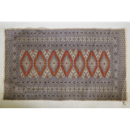 1180 - A Persian wool rug with a triple diamond medallion design on a terracotta field with beige borders, ... 