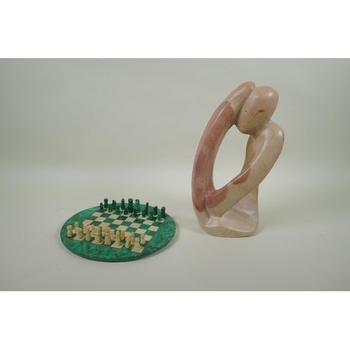 102 - A malachite and alabaster chess set, and an African carved soapstone abstract figure, 29cm high