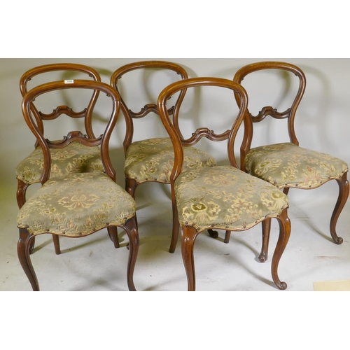 1094 - A set of five Victorian walnut balloon back dining chairs with carved backs, raised on cabriole supp... 