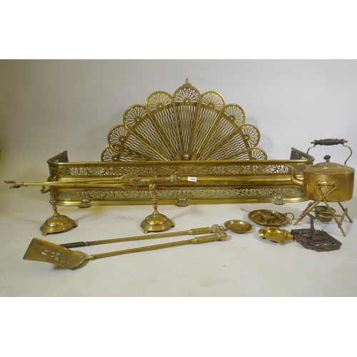 1104 - A Victorian pierced brass fire fender, 125cm long, a fan shaped fire guard, fire irons, spirit kettl... 