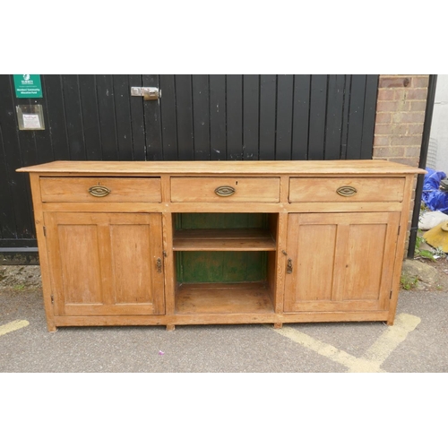 1121 - An early C19th stripped pine dresser base, three drawers over two cupboards flanking a dog kennel, r... 